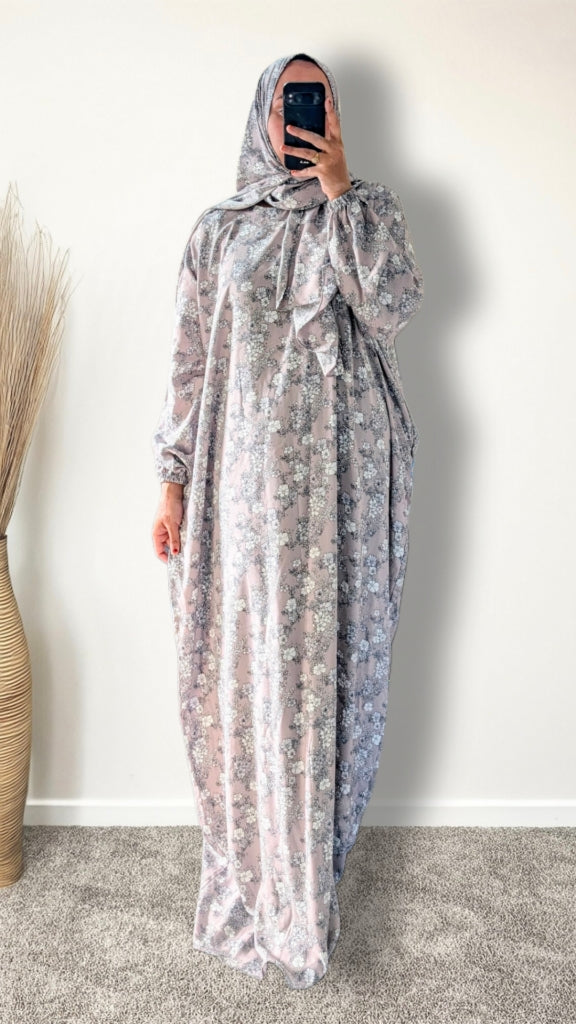 Muslim women wearing dusty mauve floral print prayer abaya with matching hijab on plain studio background