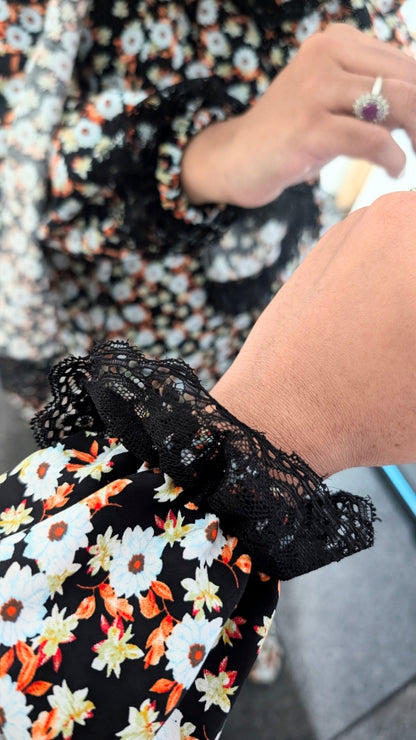 Person wearing a black lace sleeve with floral dress