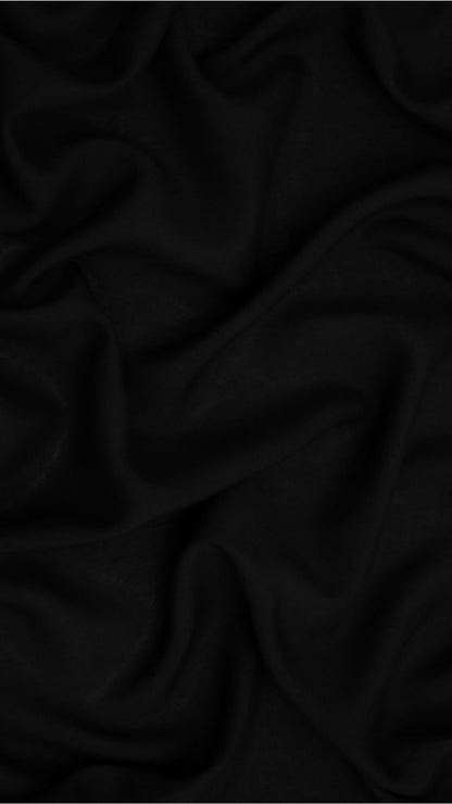 A close-up of draped black fabric with soft folds and a smooth texture filling the frame.