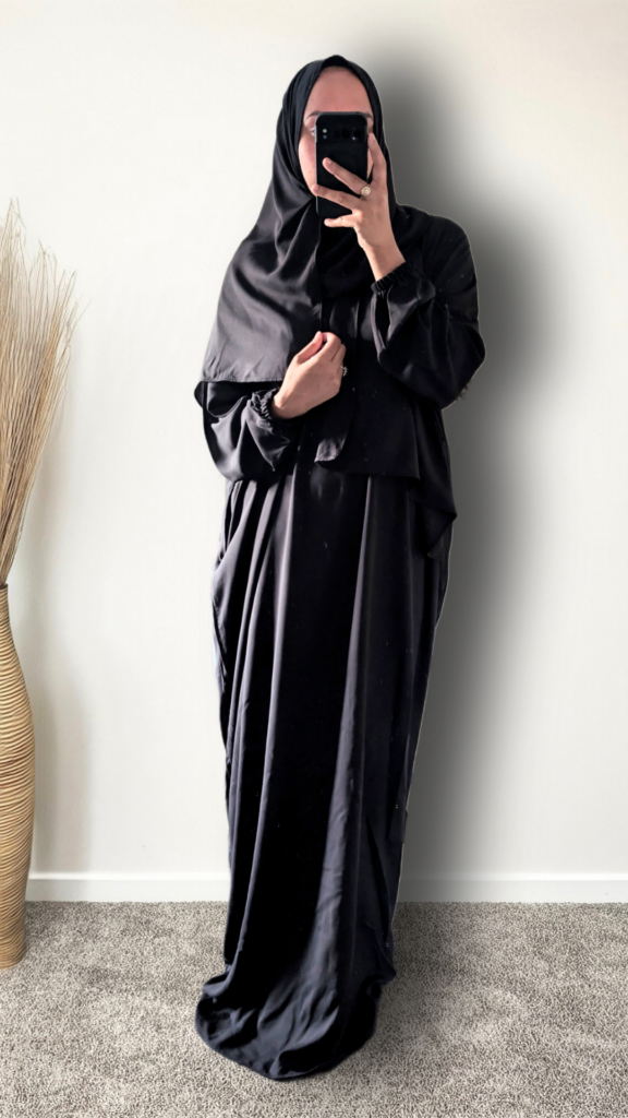 Muslim women wearing blackk plain viscose rayon prayer abaya with matching hijab on plain studio 