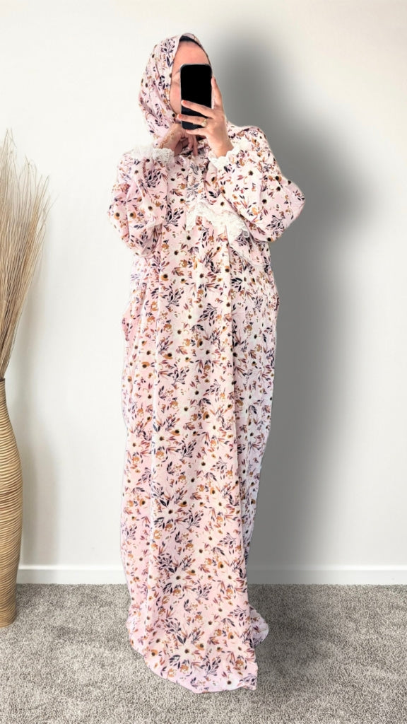 Muslim women wearing blush pink with meadow floral  print prayer abaya with matching hijab on plain studio background