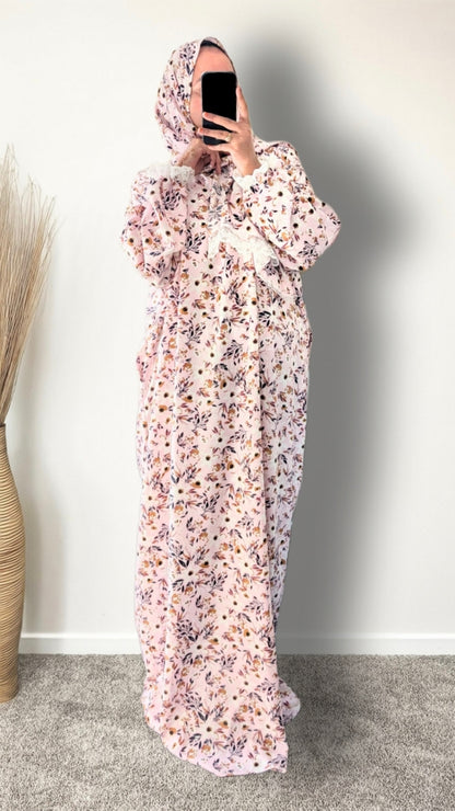 Muslim women wearing blush pink with meadow floral  print prayer abaya with matching hijab on plain studio background