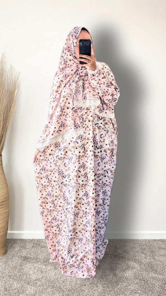 Muslim women wearing blush pink with meadow floral  print prayer abaya with matching hijab on plain studio background
