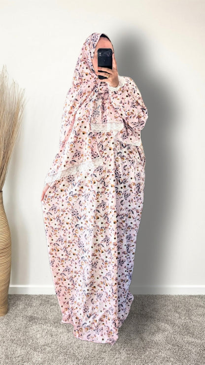 Muslim women wearing blush pink with meadow floral  print prayer abaya with matching hijab on plain studio background