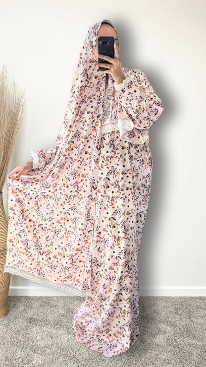 Muslim women wearing blush pink with meadow floral  print prayer abaya with matching hijab on plain studio background