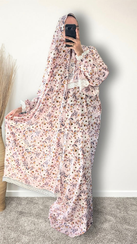 Muslim women wearing blush pink with meadow floral  print prayer abaya with matching hijab on plain studio background