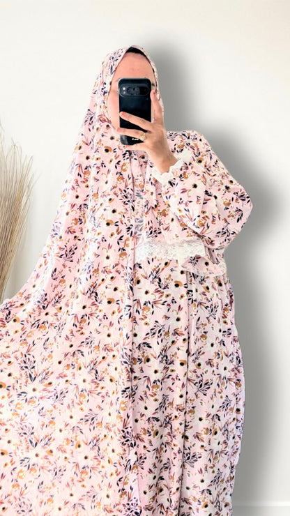 Muslim women wearing blush pink with meadow floral  print prayer abaya with matching hijab on plain studio background