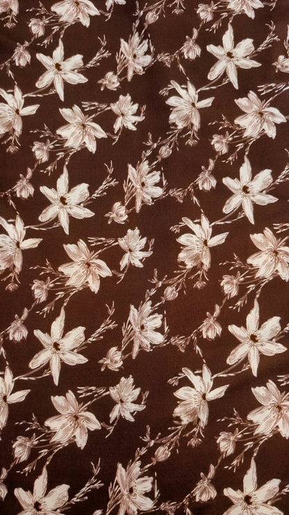 Brown fabric with a repeating floral pattern in a light beige or cream tone.