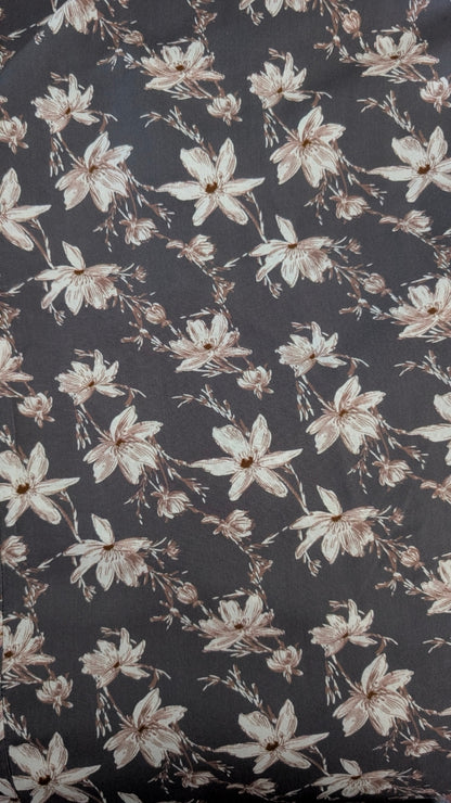 A close-up of a dark charcoal gray fabric with a repeating floral pattern of cream and light brown blossoms.