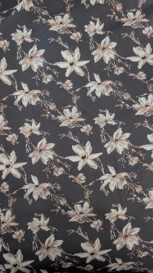 A close-up of a dark charcoal gray fabric with a repeating floral pattern of cream and light brown blossoms.