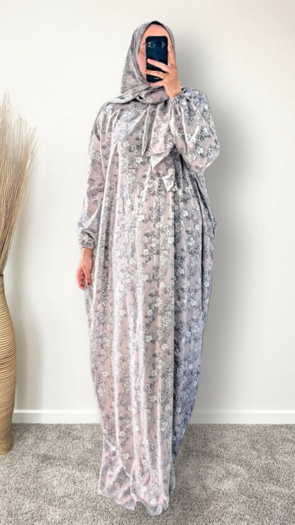 Muslim women wearing dusty mauve floral print prayer abaya with matching hijab on plain studio background