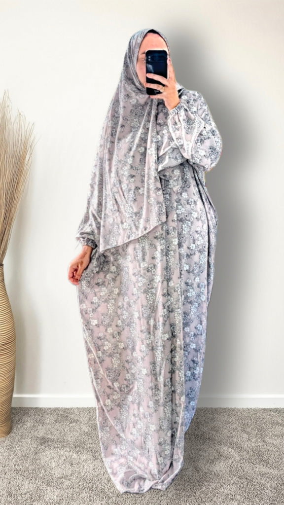 Muslim women wearing dusty mauve floral print prayer abaya with matching hijab on plain studio background