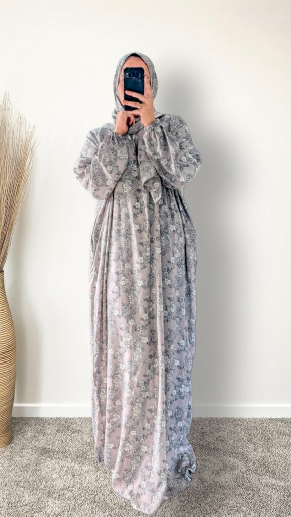 Muslim women wearing dusty mauve floral print prayer abaya with matching hijab on plain studio background