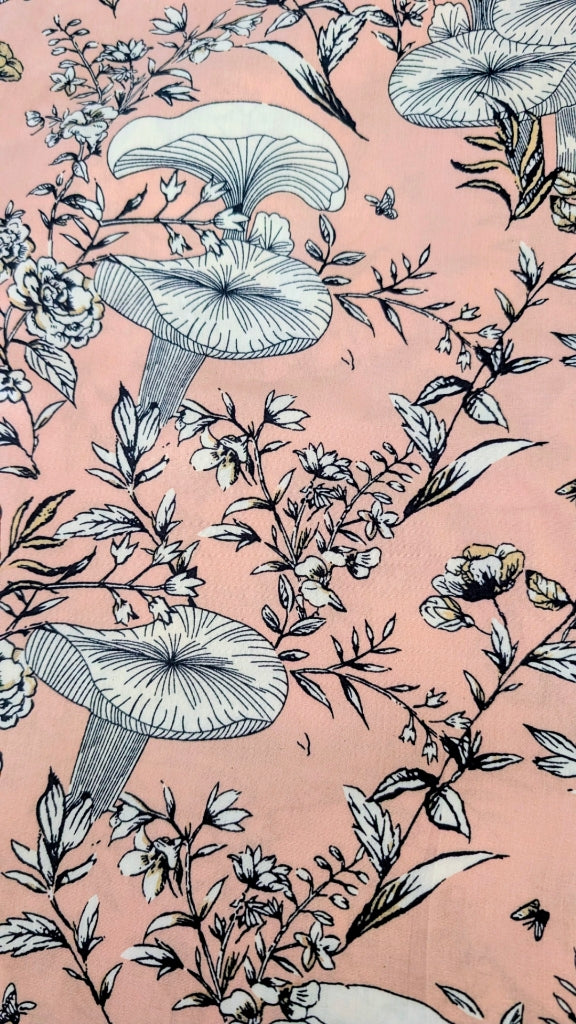 A close-up of a pink fabric featuring a detailed botanical pattern with mushrooms, flowers, and leaves in black and white line art.