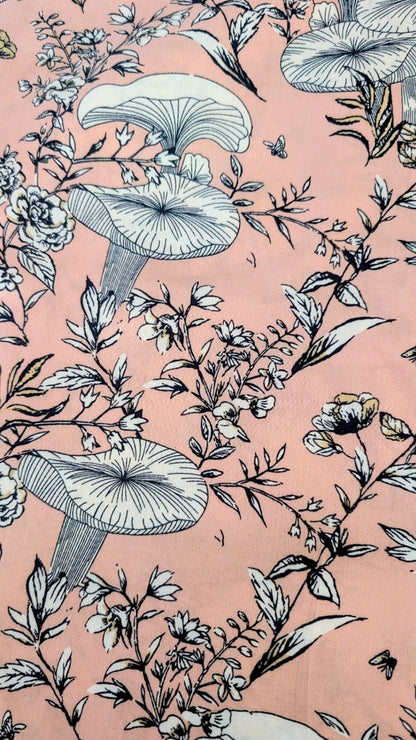 A close-up of a pink fabric featuring a detailed botanical pattern with mushrooms, flowers, and leaves in black and white line art.