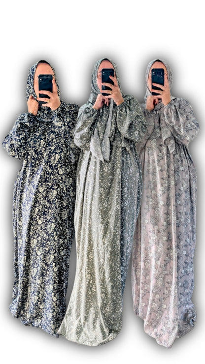 Three identical  abay floral botanical print withc matching hijab in different colors held by a person against a white background
