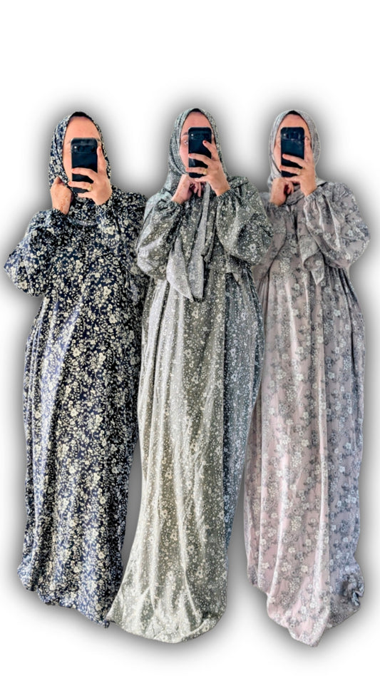 Three identical  abay floral botanical print withc matching hijab in different colors held by a person against a white background
